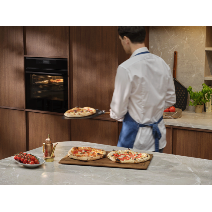 Person with the pizza expert oven and pizza peel tray with Neapolitan pizzas