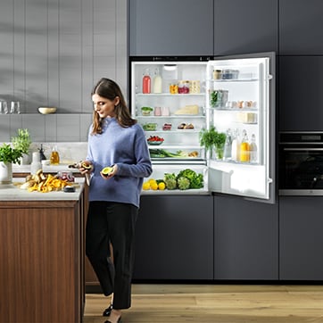 Woman in kitchen with open fridge in background